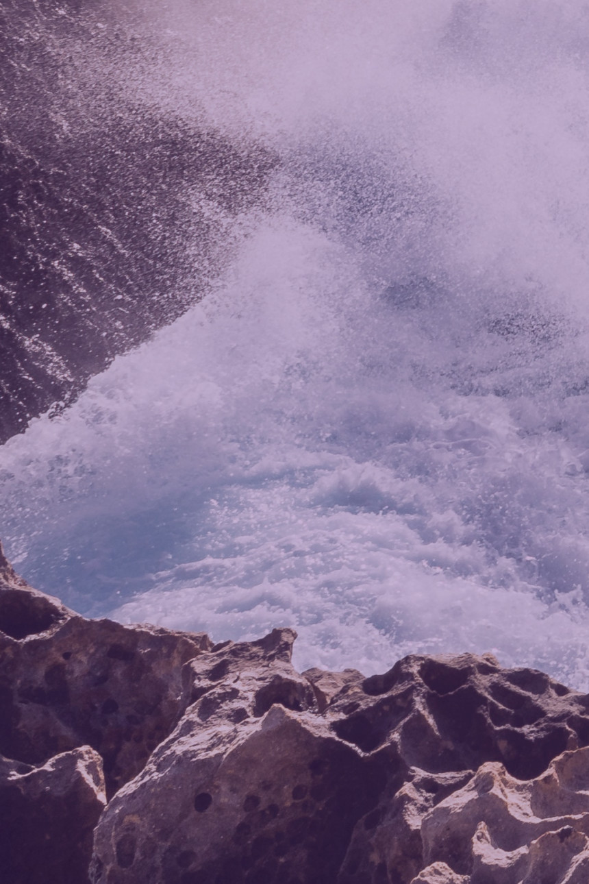 A wave crushing rocks large image 