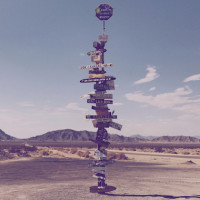 Ein kleines Bild eines Postens voll mit Schildern in der Wüste | HudsonGoodman