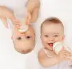 twee lachende baby's met hun melkfles op een laken