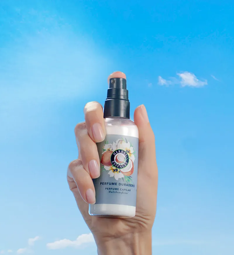 Una mano sosteniendo el Perfume Capilar Duradero con notas de coco