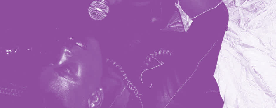 A purple tinted image of MHYSA signing into a microphone