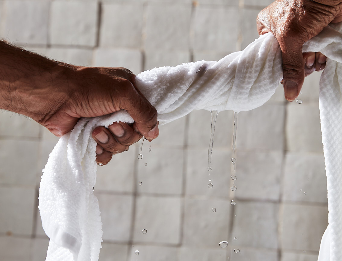 Hands wringing out a Waffle Terry Bath Towel in White