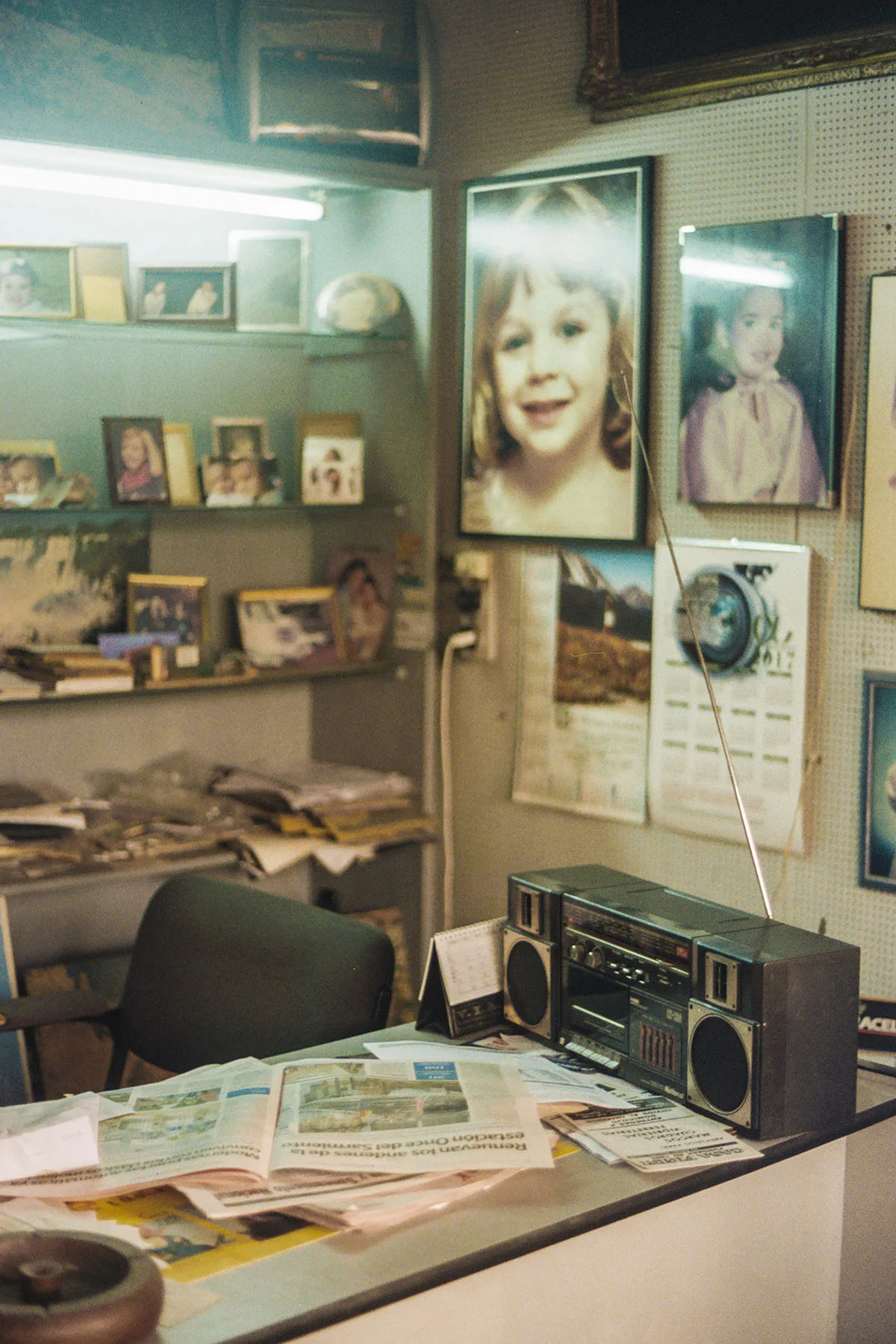 A photo of an office in Buenos Aires taken by Maxi Magnano. Framed photos adorn the walls around a desk that holds a stereo system and an open newspaper.