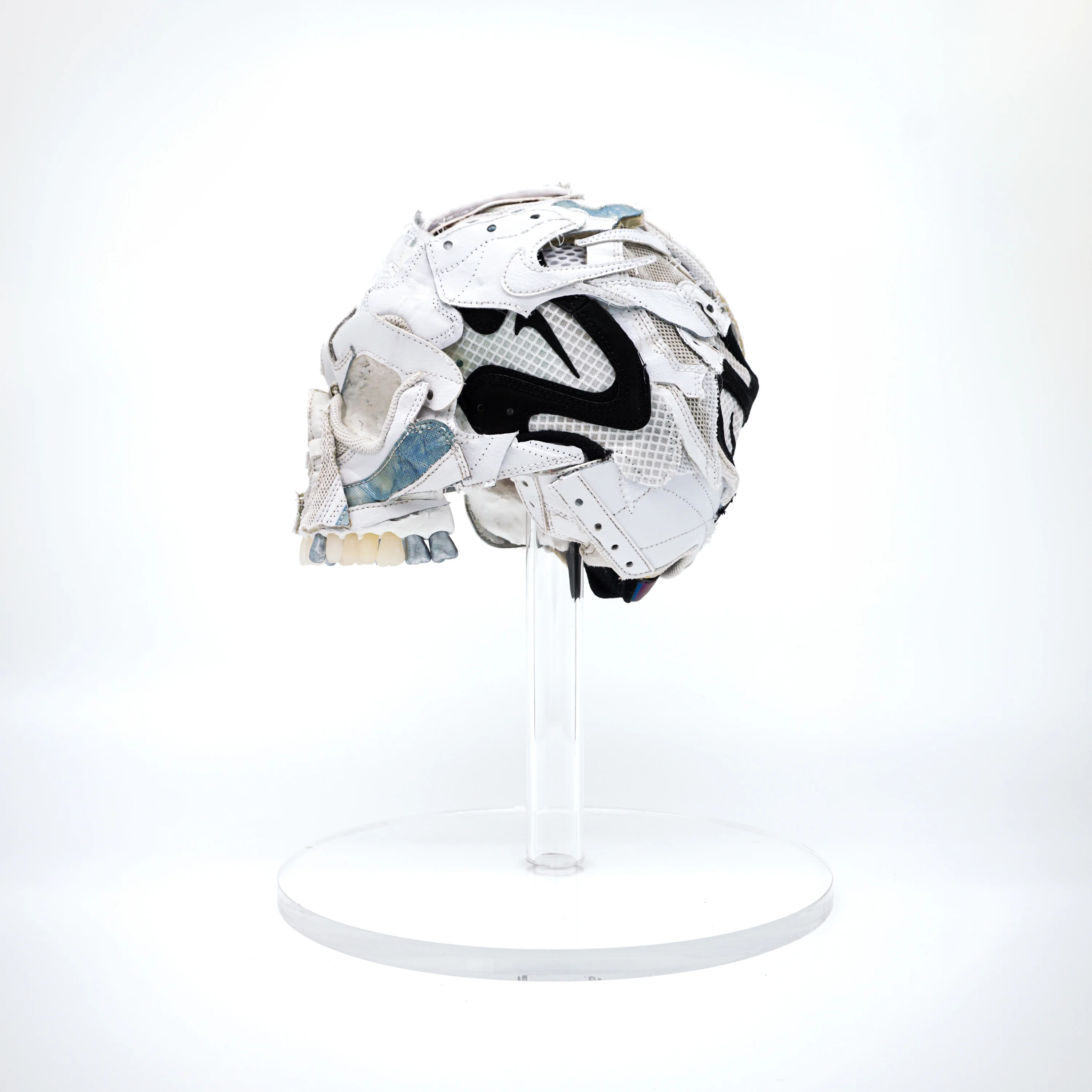 A photograph of a sculpture of a skull, made from pieces of sneakers that have been cut up and painted.