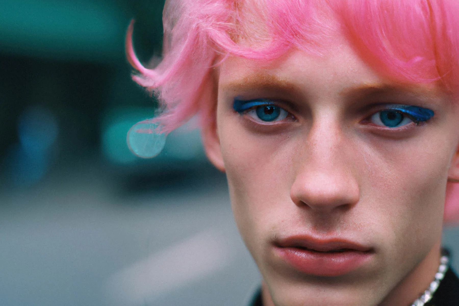An AI-generated photograph showing a person with bright pink hair and wearing blue eyeliner staring into the camera