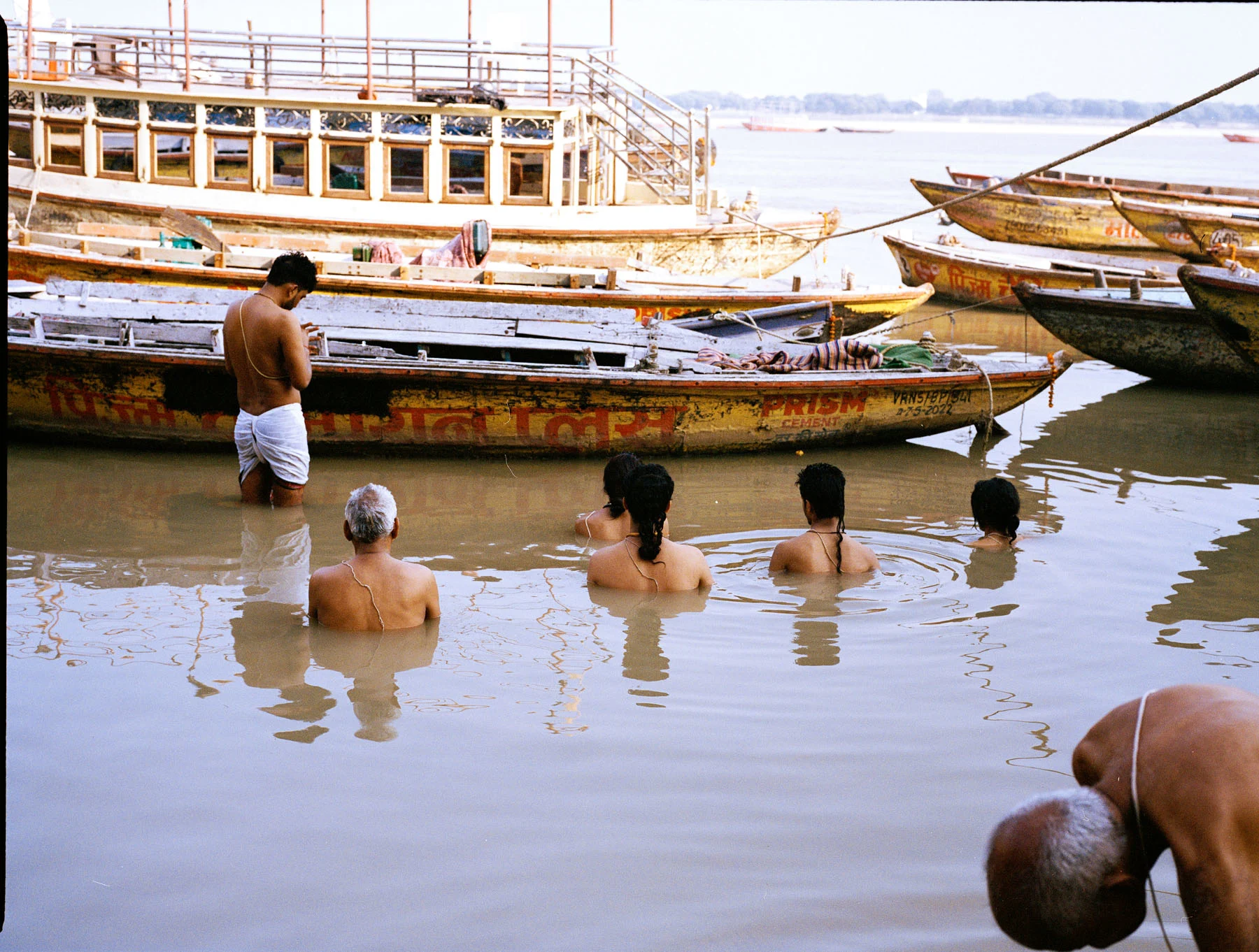 A photograph of people praying while submerged in the river Ganges, in Varanasi.