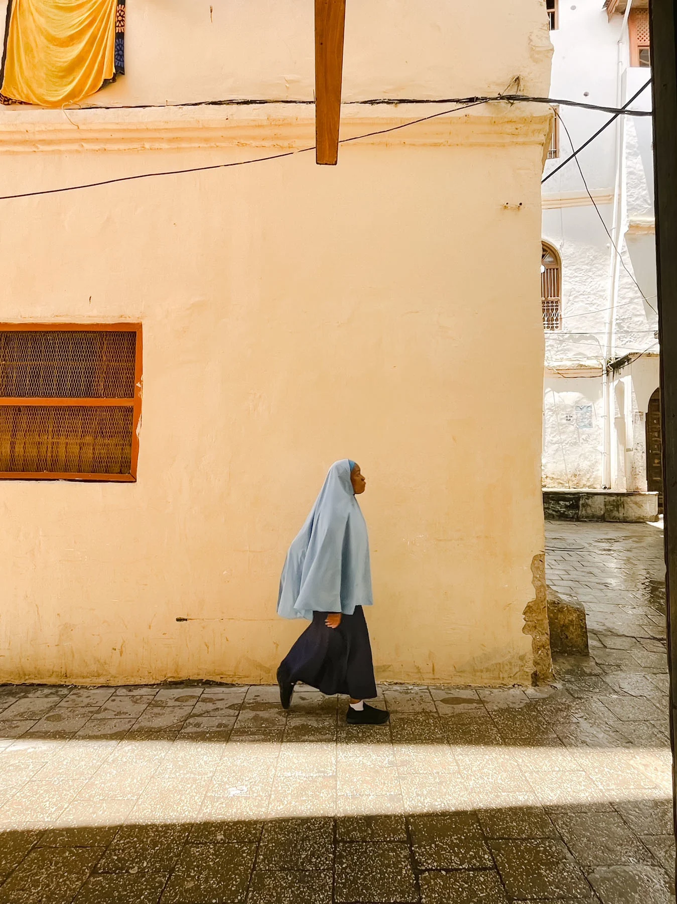 A photograph of a girl walking along a street in Zanzibar, Tanzania. 