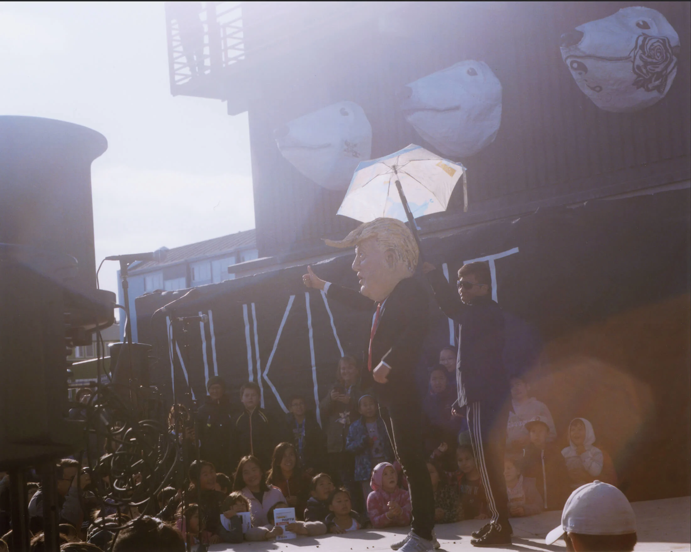 A man wearing a mask of Donald Trump on stage, during a carnival in Nuuk. | One of Nuuk’s old housing blocks.