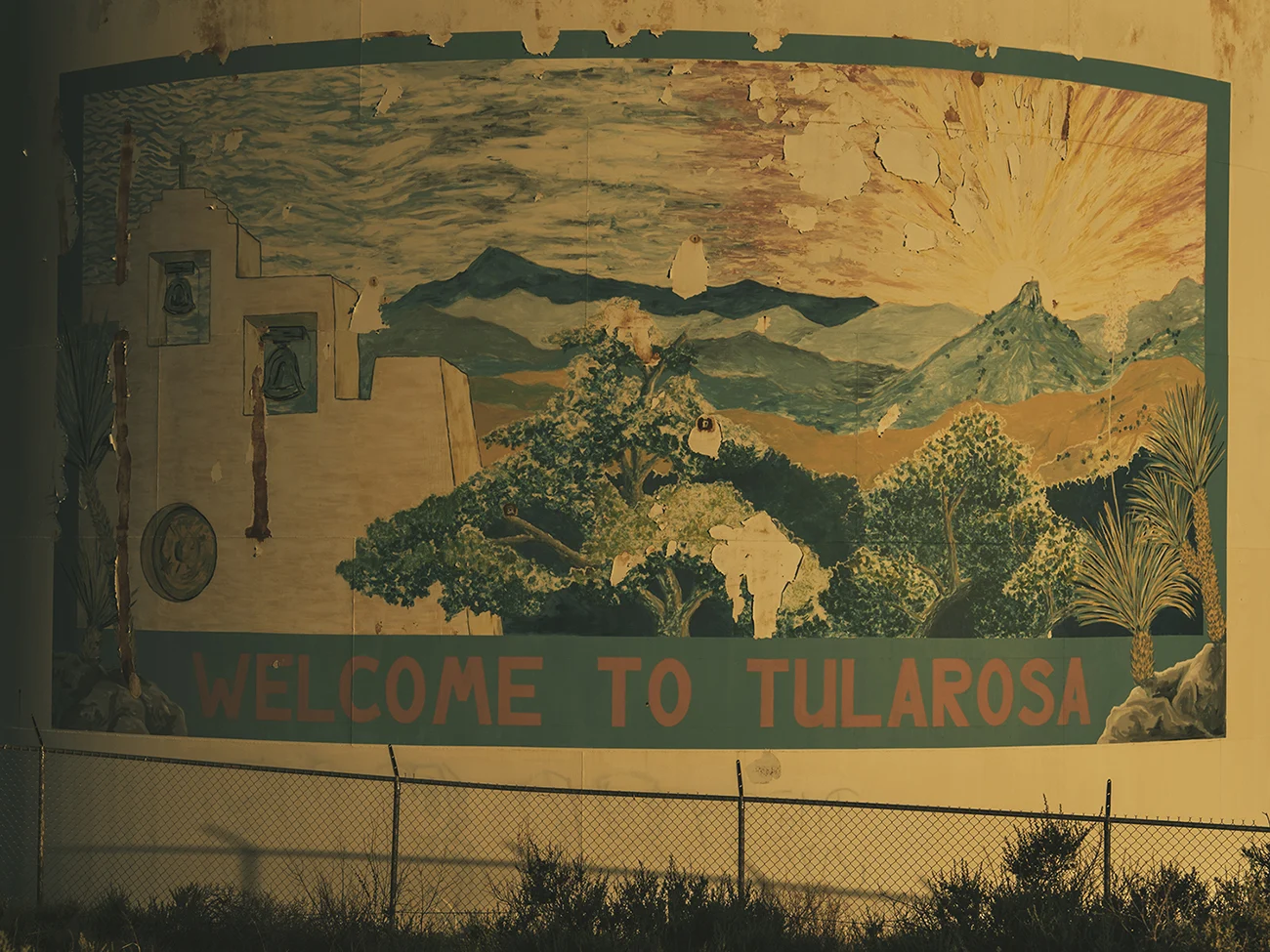A painting of the rising sun over a church on a silo at Tularosa