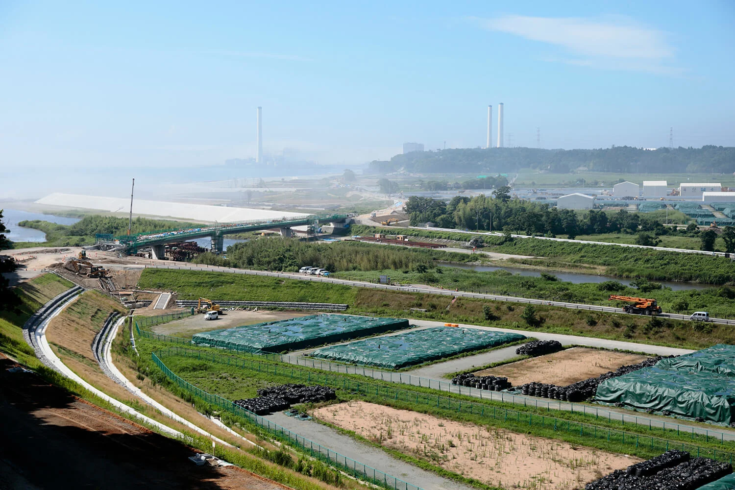 Naraha, 20km from Fukushima Daiichi Nuclear Power Plant. Temporary storage of the waste collected by decontamination works in the foreground, and the reconstruction of the embankment destroyed in the tsunami on the left.