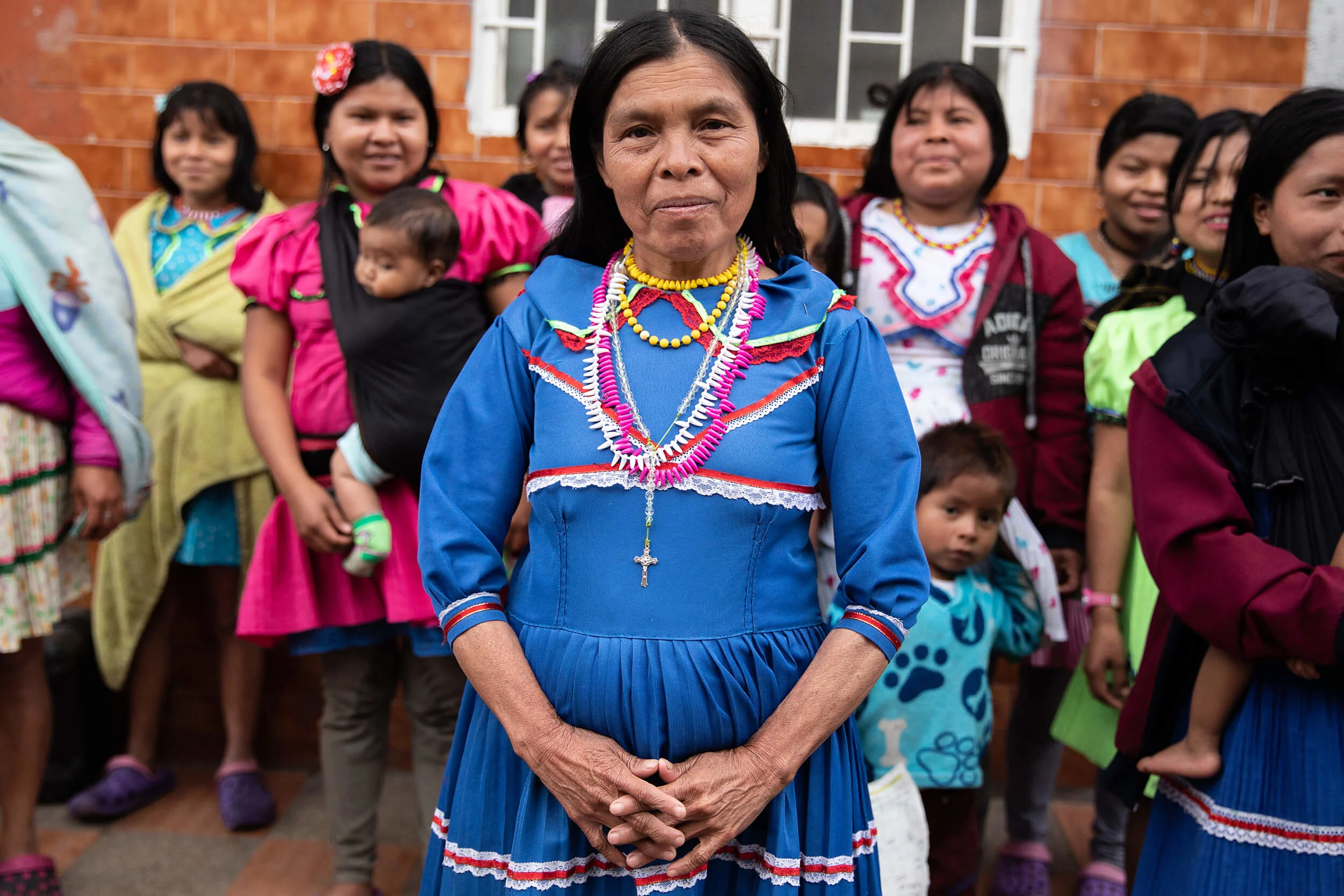 Left: A swaddled child sleeps on his concerned mother’s chest. The murder in the community left everyone tense and on edge. Right: Embera women assemble outside of their building before a meeting to discuss the future of the community