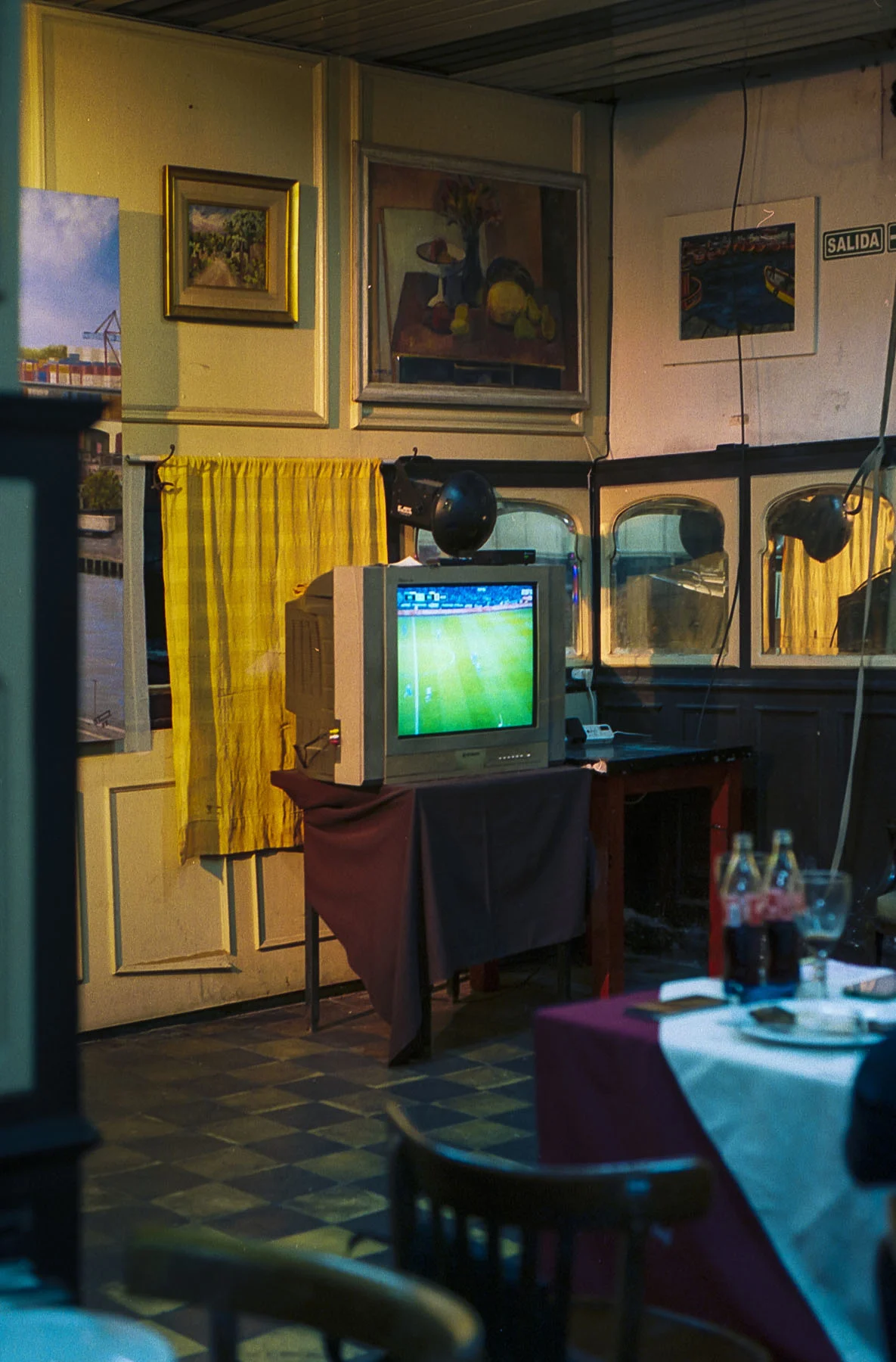 A photo of the inside of a bar in Buenos Aires taken by Maxi Magnano. A TV sits on a table, a football match playing on its screen.