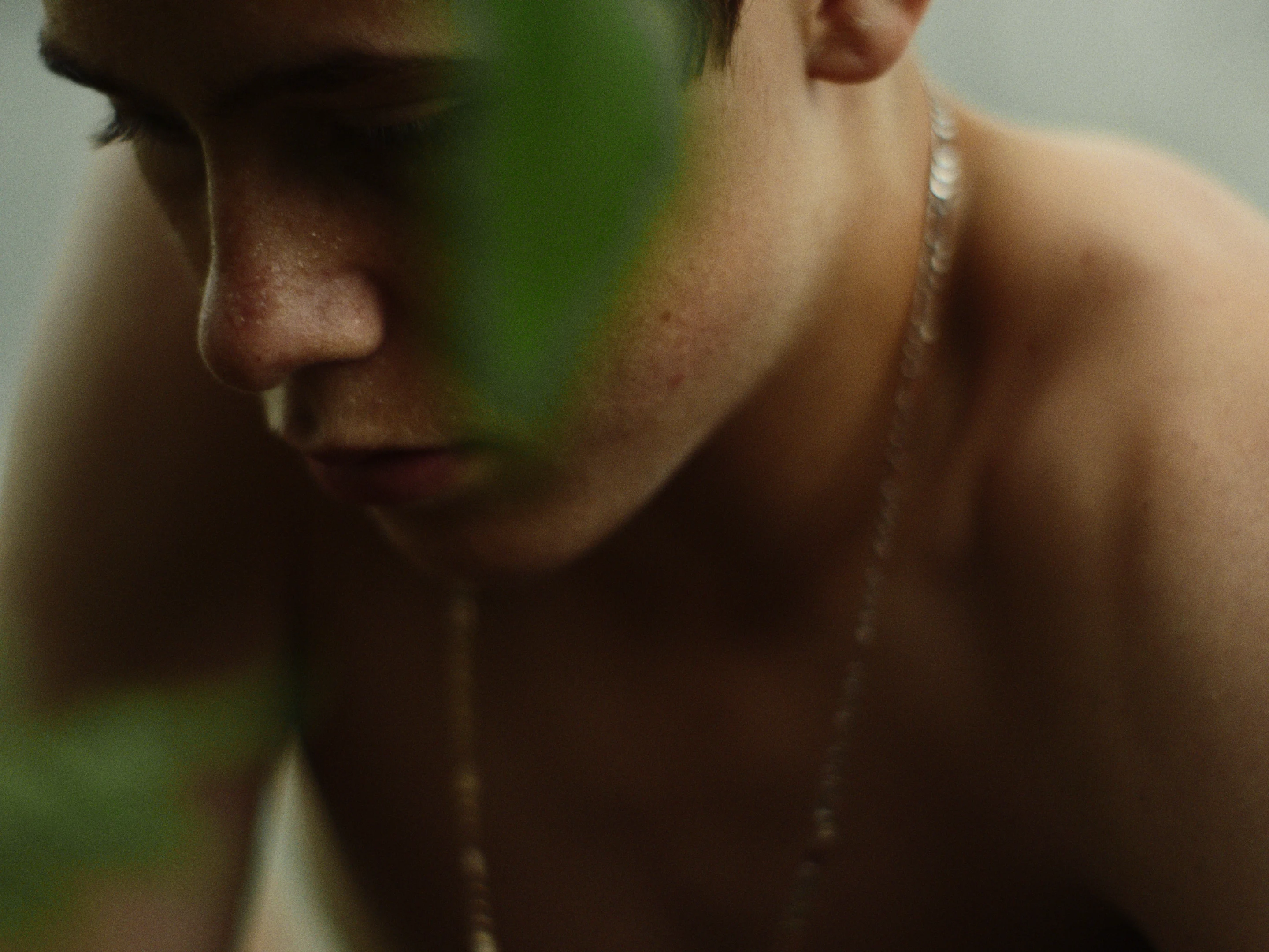 A still from the movie "Invincible" featuring Marc-Antoine Bernier, played by actor Léokim Beaumier-Lépine, working in a garden, lost in thought.