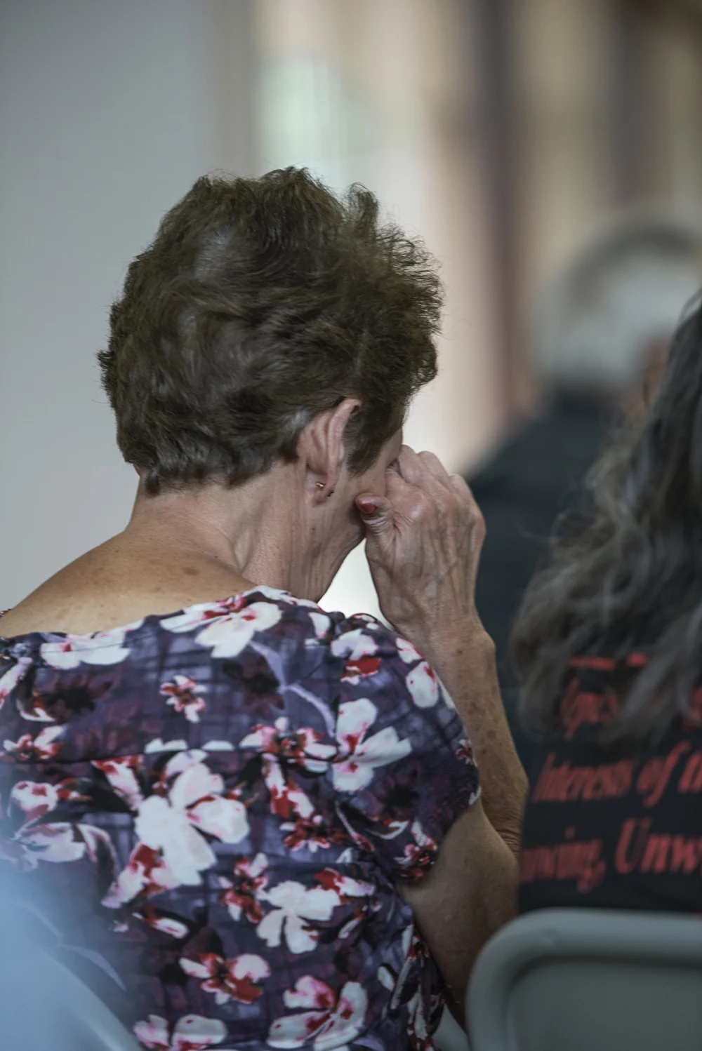A woman wipes away tears after hearing first hand accounts of the survivors at the same meeting.