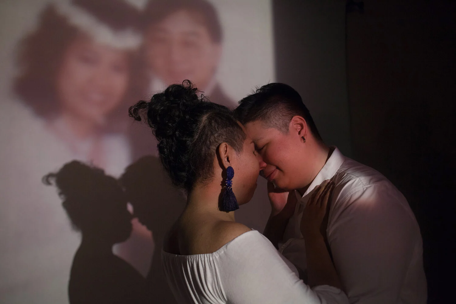 Fi and Liting embrace in front of a wedding portrait of Liting's parents. They envisage walking down the aisle to Young Volcanoes by Fall Out Boy.