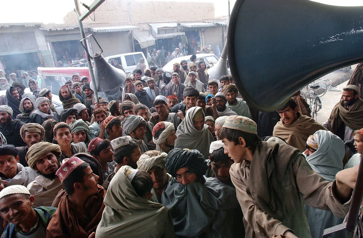 Afghans gather around the speakers of a music store on the streets of Kandahar, Afghanistan, December 12, 2001. © Lynsey Addario