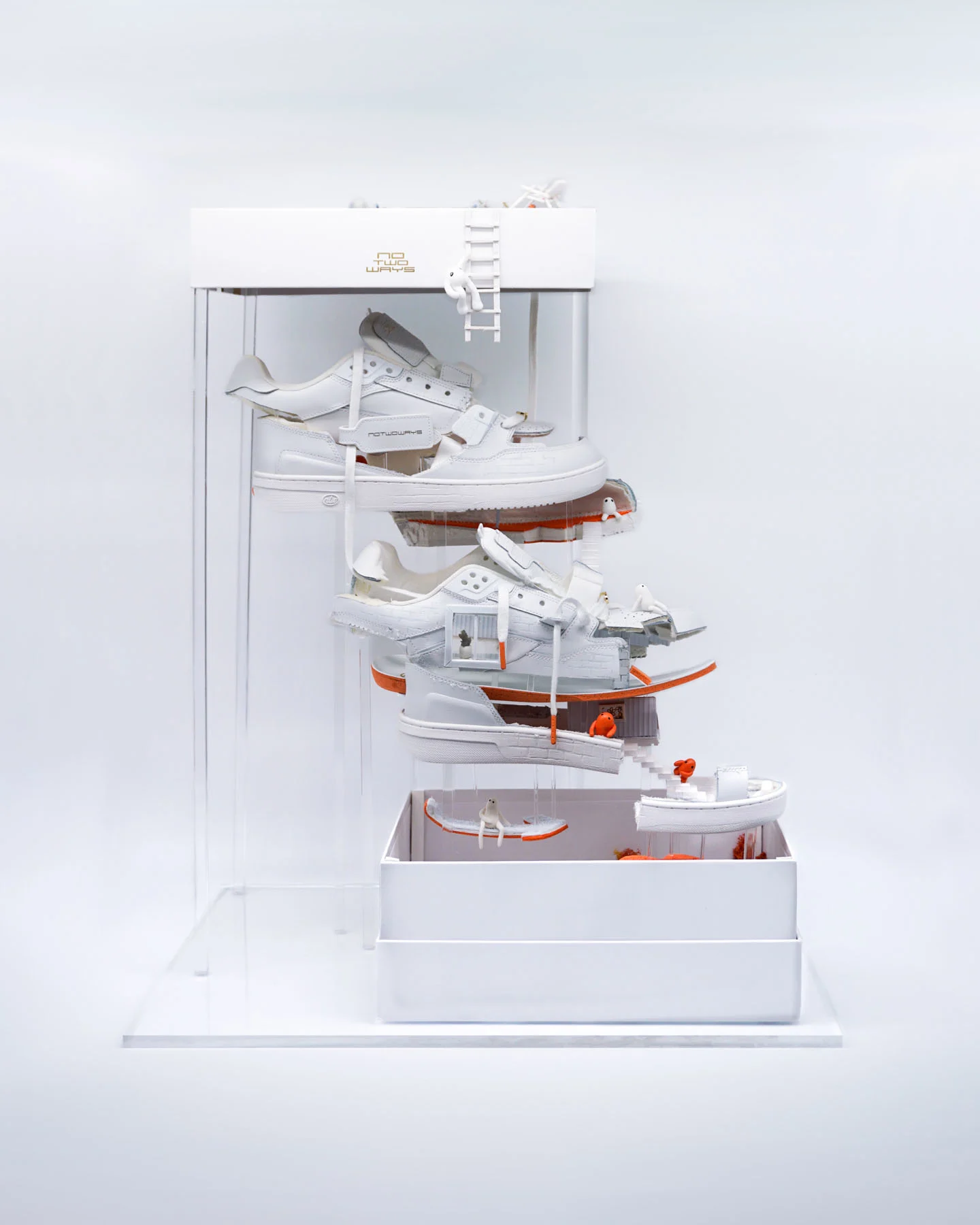 A photograph of a sculpture involving a sneaker separated into vertical layers to create an apartment. Inside the apartment are small orange figures, a pool, garden and stairs between each floor. 