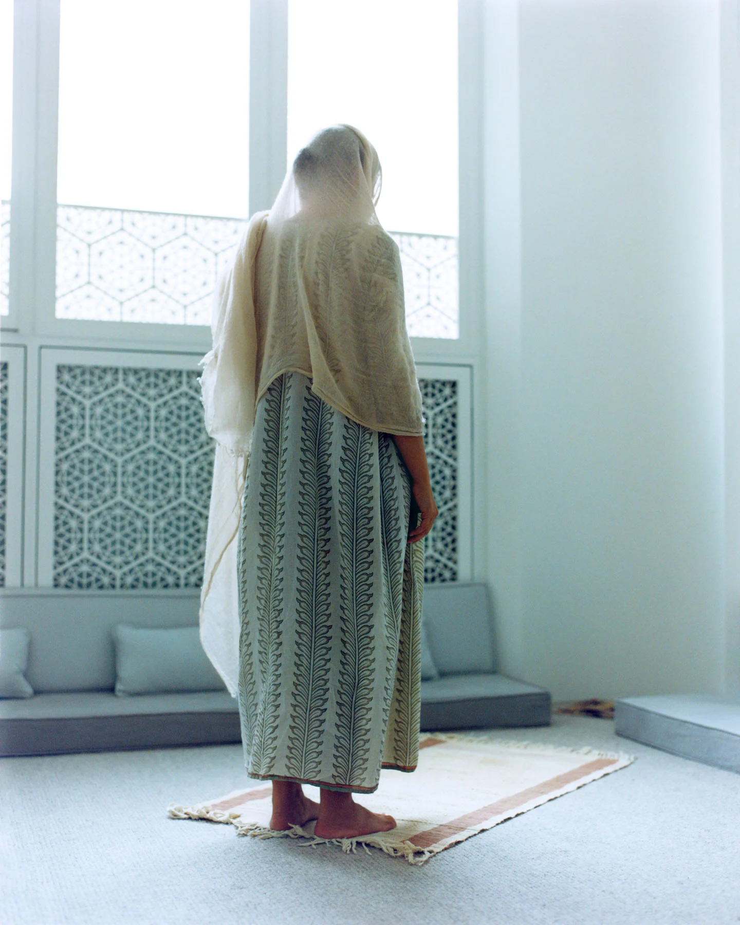 A photograph of architect Nevine Nasser, taken from behind as she stands in prayer at the Sufi centre.