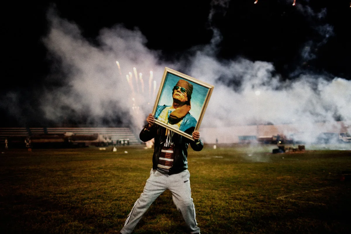 A Qaddafi supporter holds a portrait of the Libyan leader during a celebration staged for a group of visiting foreign journalists after regime forces re-took the city from rebels. Zawiyah, Libya. 2011. © Moises Saman / Magnum Photos