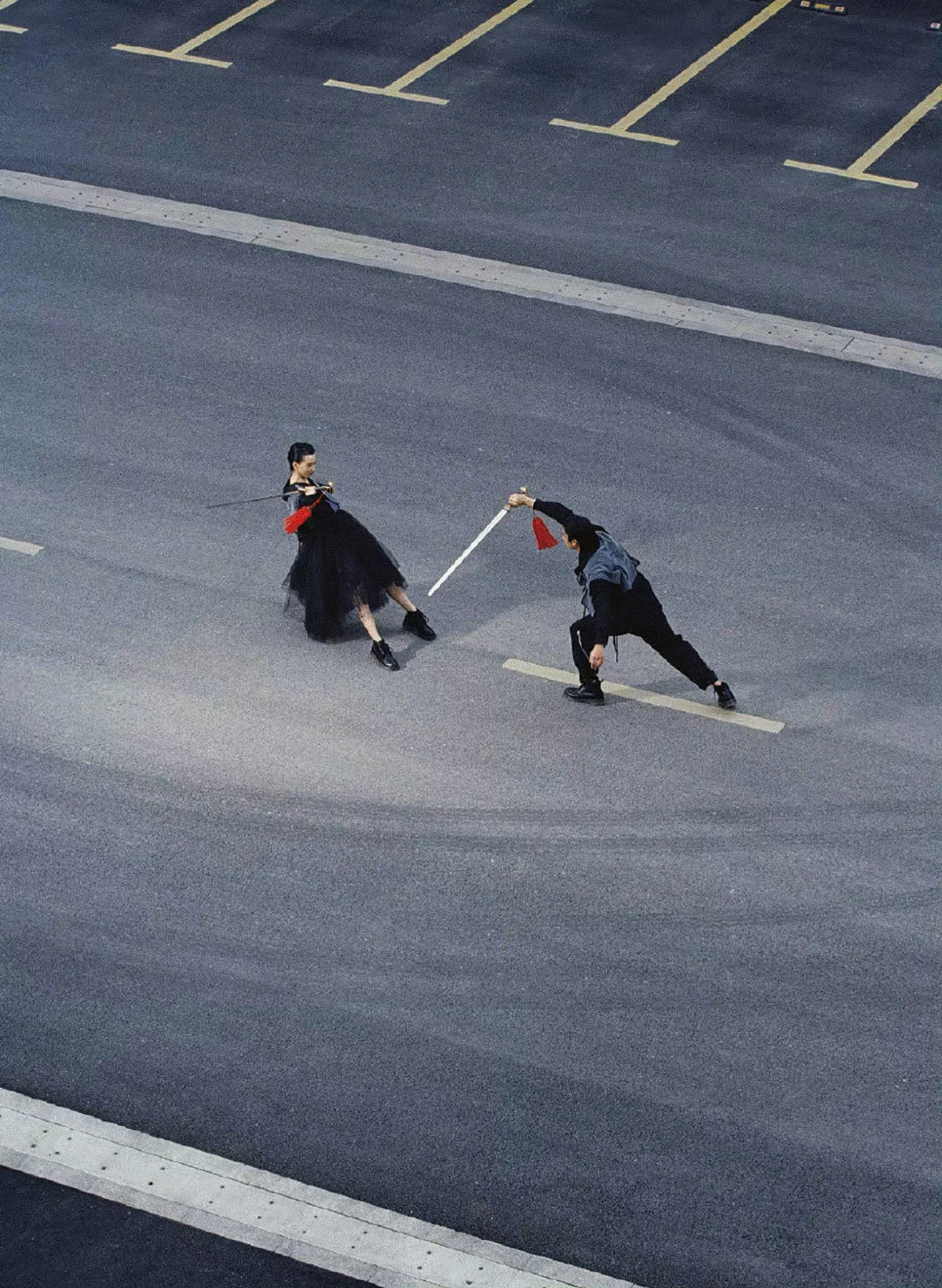 A photograph, taken from an elevated position and from a distance, featuring female model Taoye and male model Lin Wenhui facing off against each other in a sword fight.