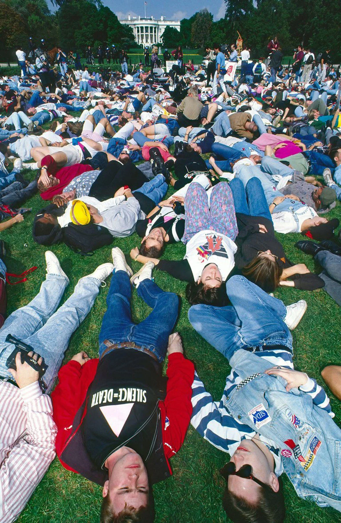 A color photograph of groups of protestors lying on the grass outside of the White House in Washington, D.C.