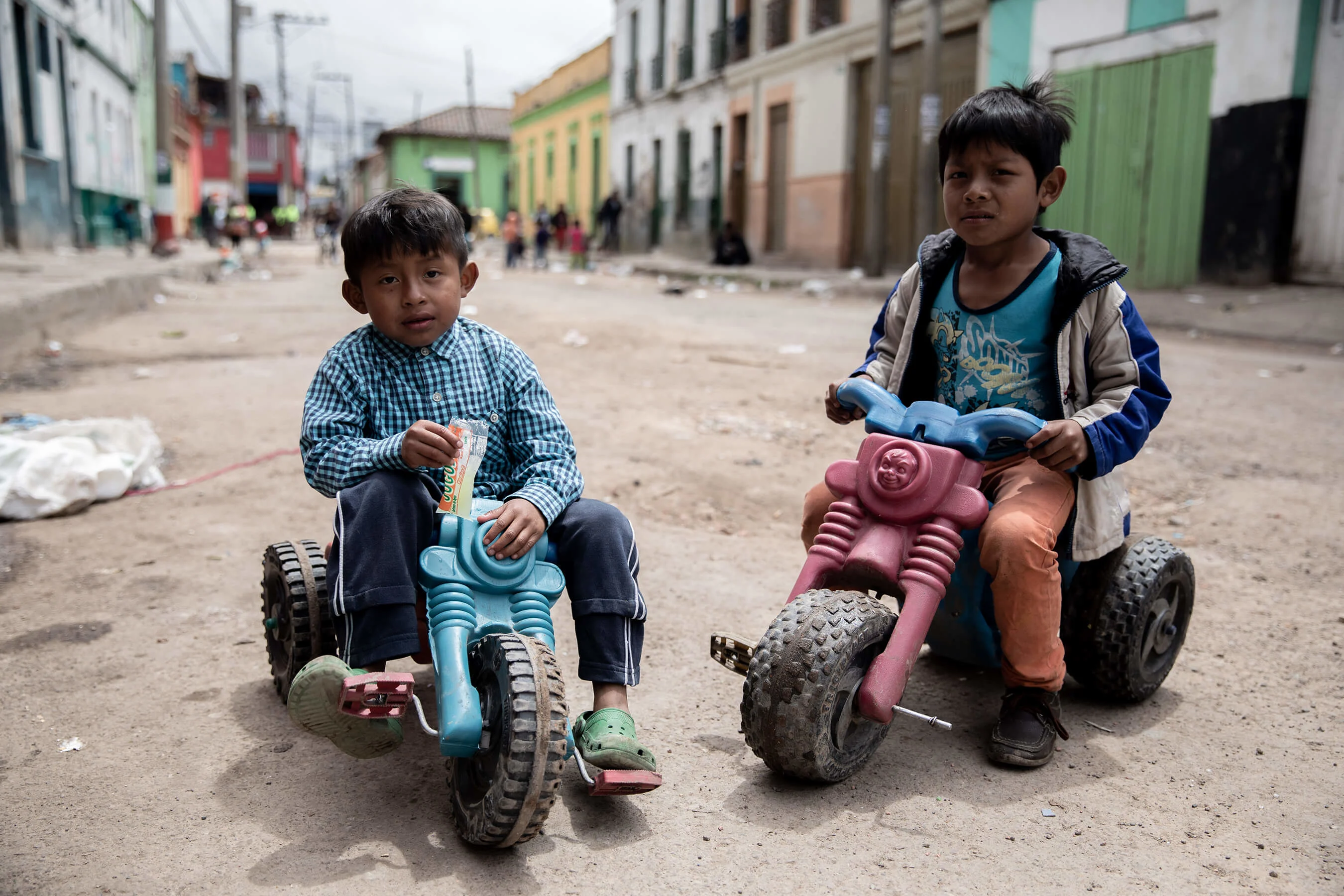 Two Embera boys from western Choco sit for a portrait on their three wheelers outside their crumbling tenement