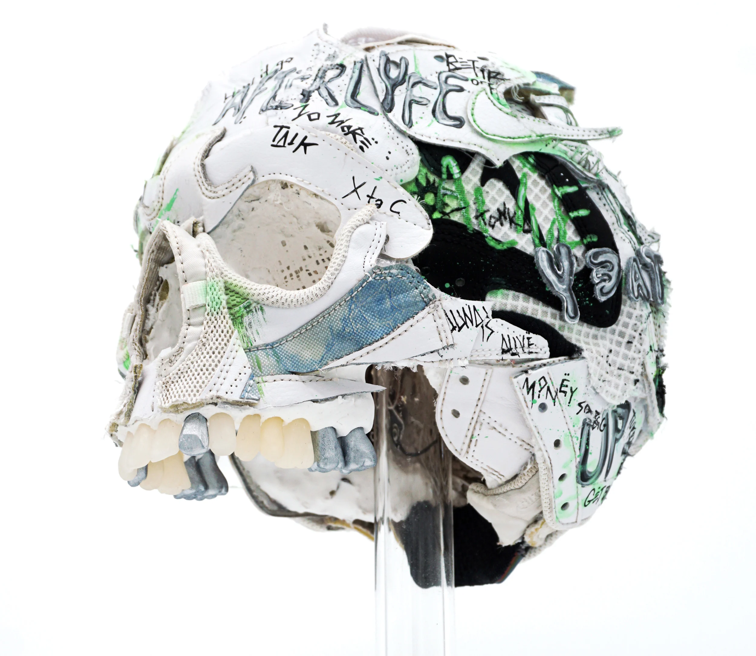 A photograph of a sculpture of a skull, made from pieces of sneakers that have been cut up and painted.
