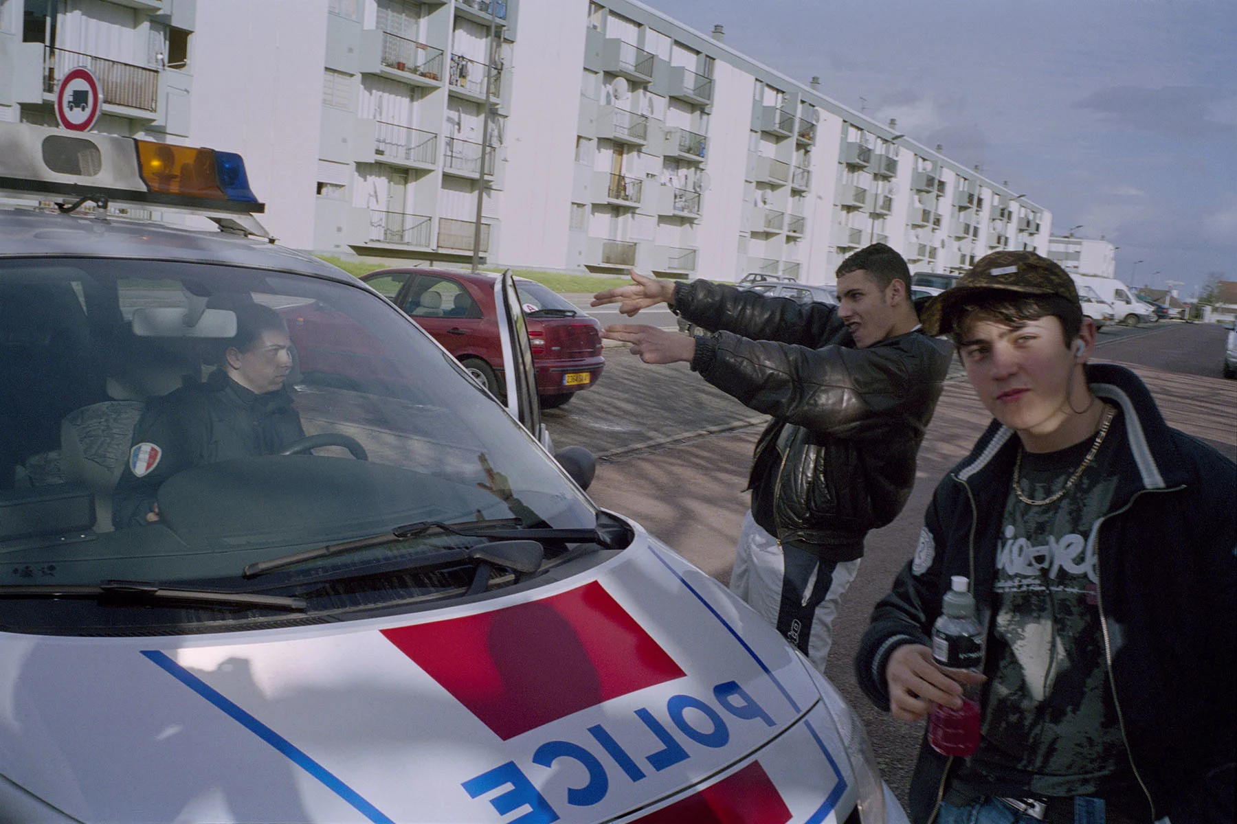 A photo of some young men hanging out around a police car.