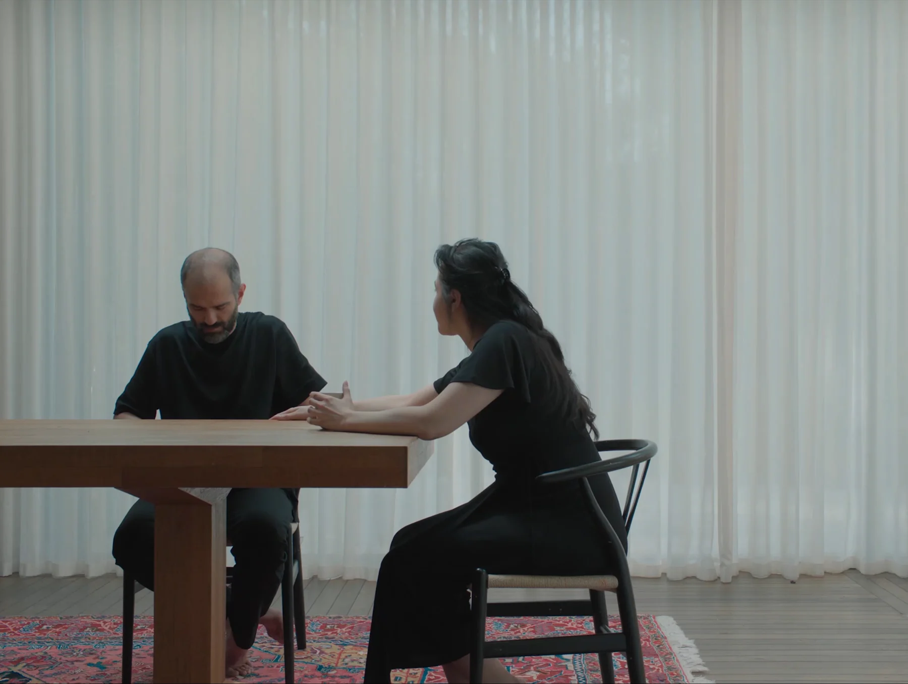A short clip from Somayeh's film “Skin of Water” showing a man and a woman sitting at a dining table as a blue butterfly flies into shot and lands on the table in front of them.