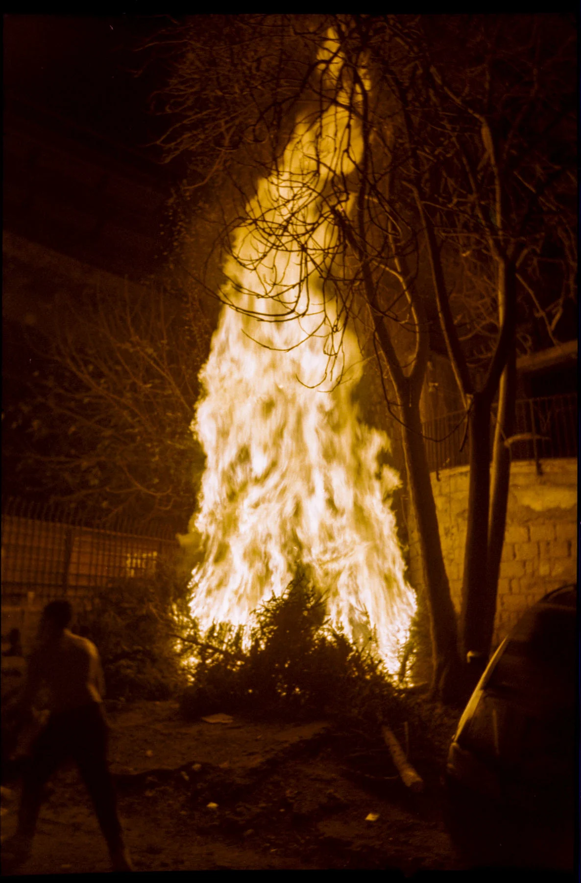 A photo of a small fire roaring in the street at night