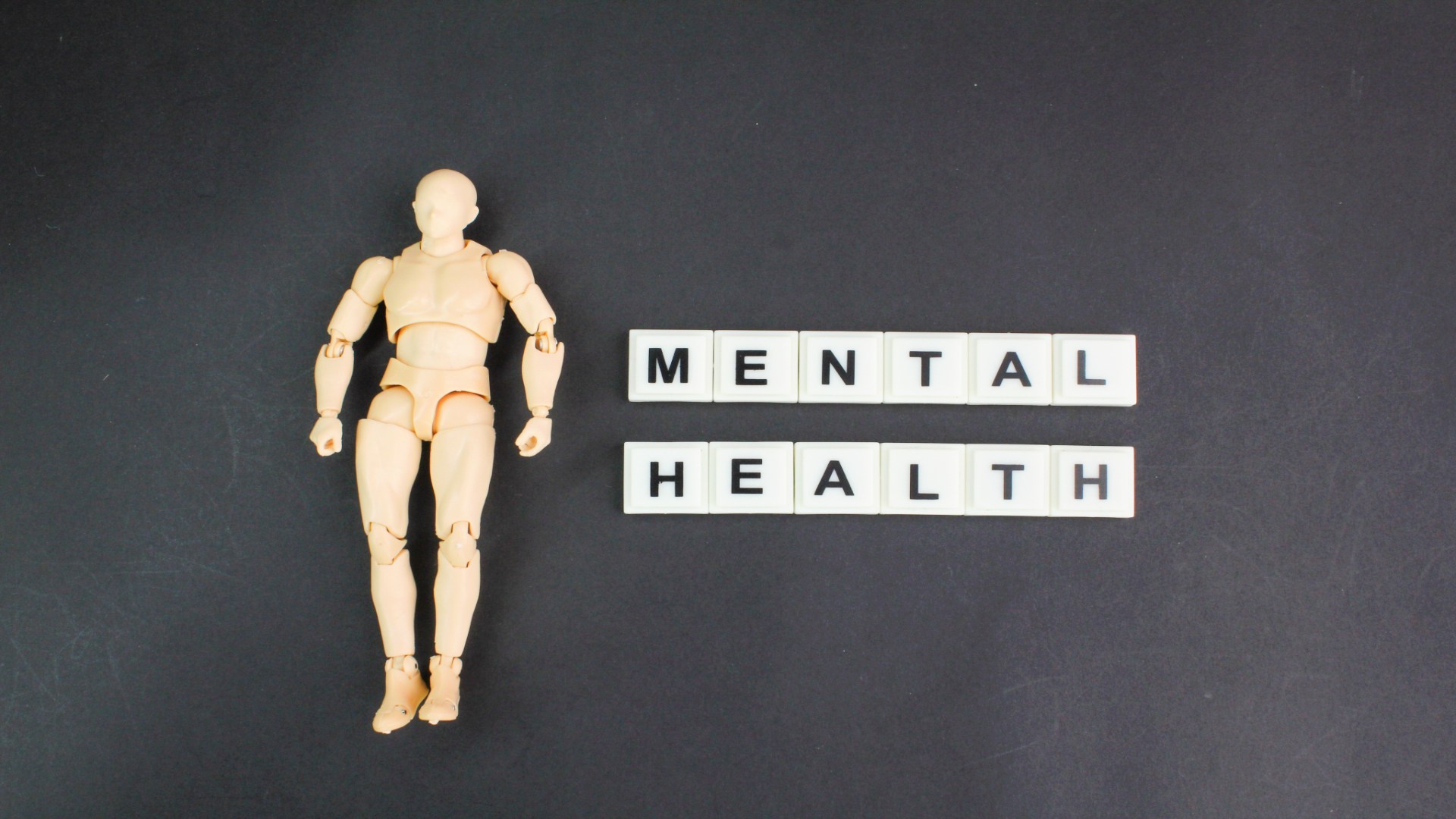 Plastic human mannequin next to the words “Mental Health” on a black background, symbolizing clinical and psychological aspects of telepsychiatry. Plastic human mannequin next to the words “Mental Health” on a black background, symbolizing clinical and psychological aspects of telepsychiatry.