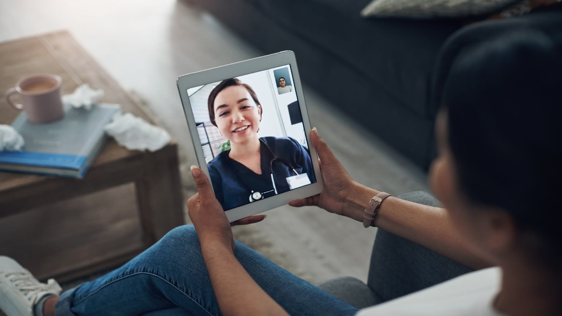 Woman attending a telehealth mental health services session on a tablet, speaking with a cheerful therapist from the comfort of home.