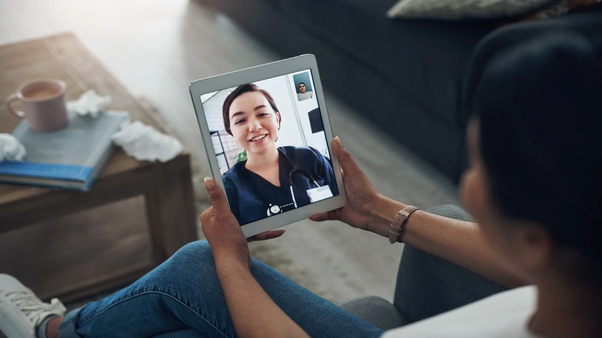Woman attending a telehealth mental health services session on a tablet, speaking with a cheerful therapist from the comfort of home.