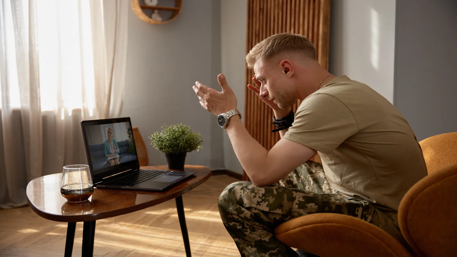 Veteran participating in online therapy for PTSD, expressing emotions during a virtual counseling session from home.