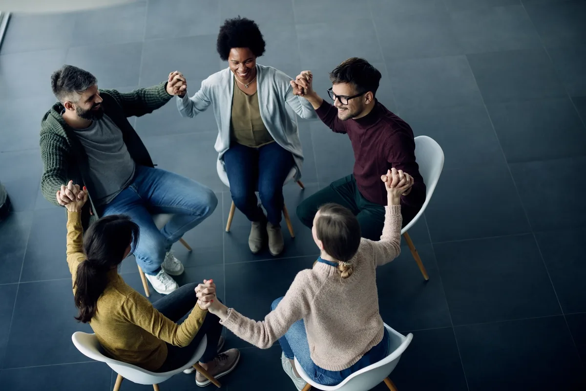 Drug Rehab: Group of people sitting in a circle holding hands