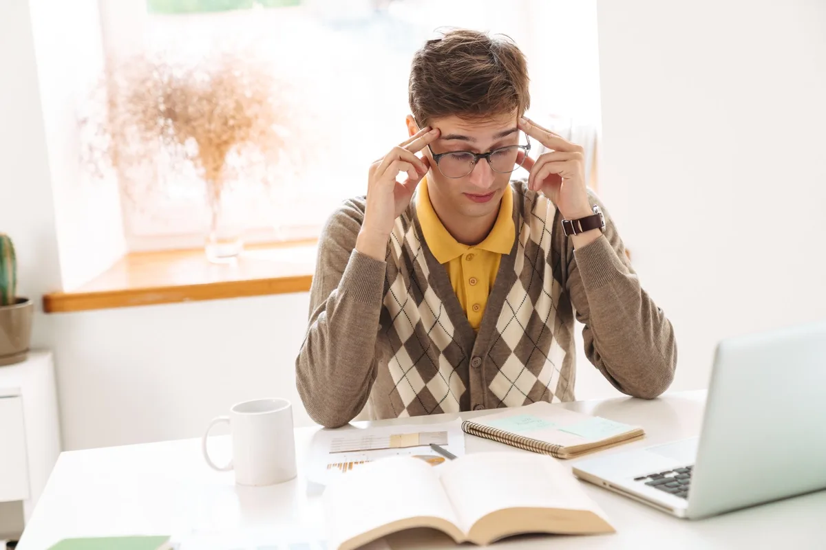 Stimulant Addiction: Man with a headache working at a desk