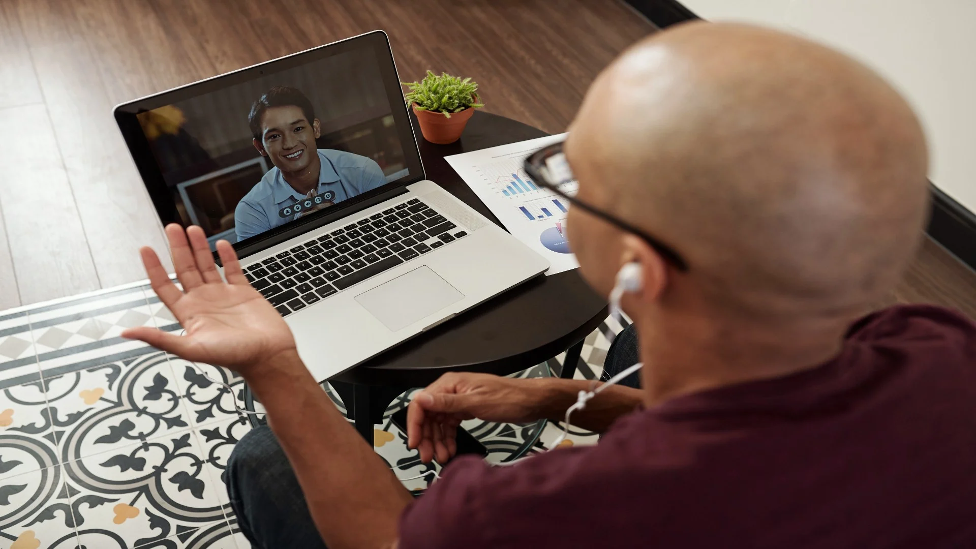 Man engaging in online therapy for PTSD, using a laptop and earbuds for a video call with a mental health professional.