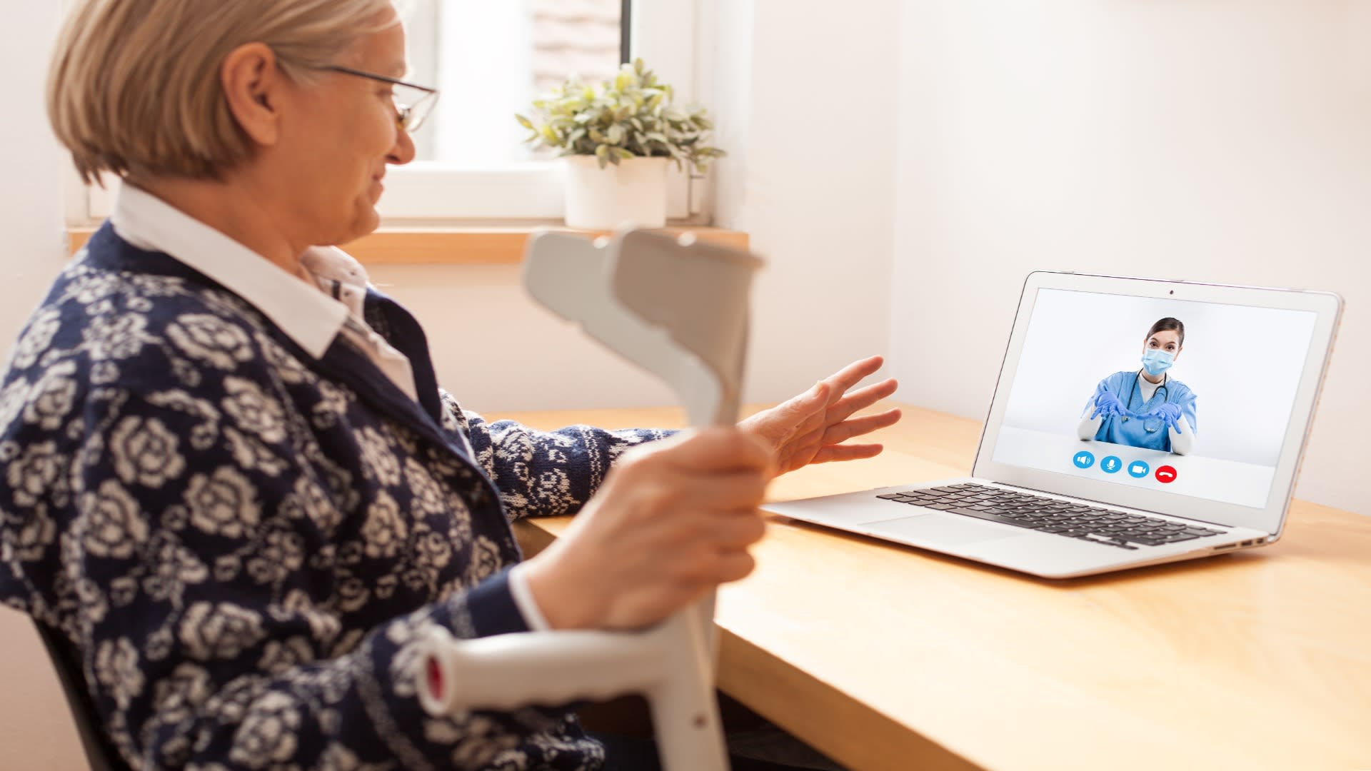 Elderly woman in recovery using telehealth opioid treatment services to consult with a nurse online.