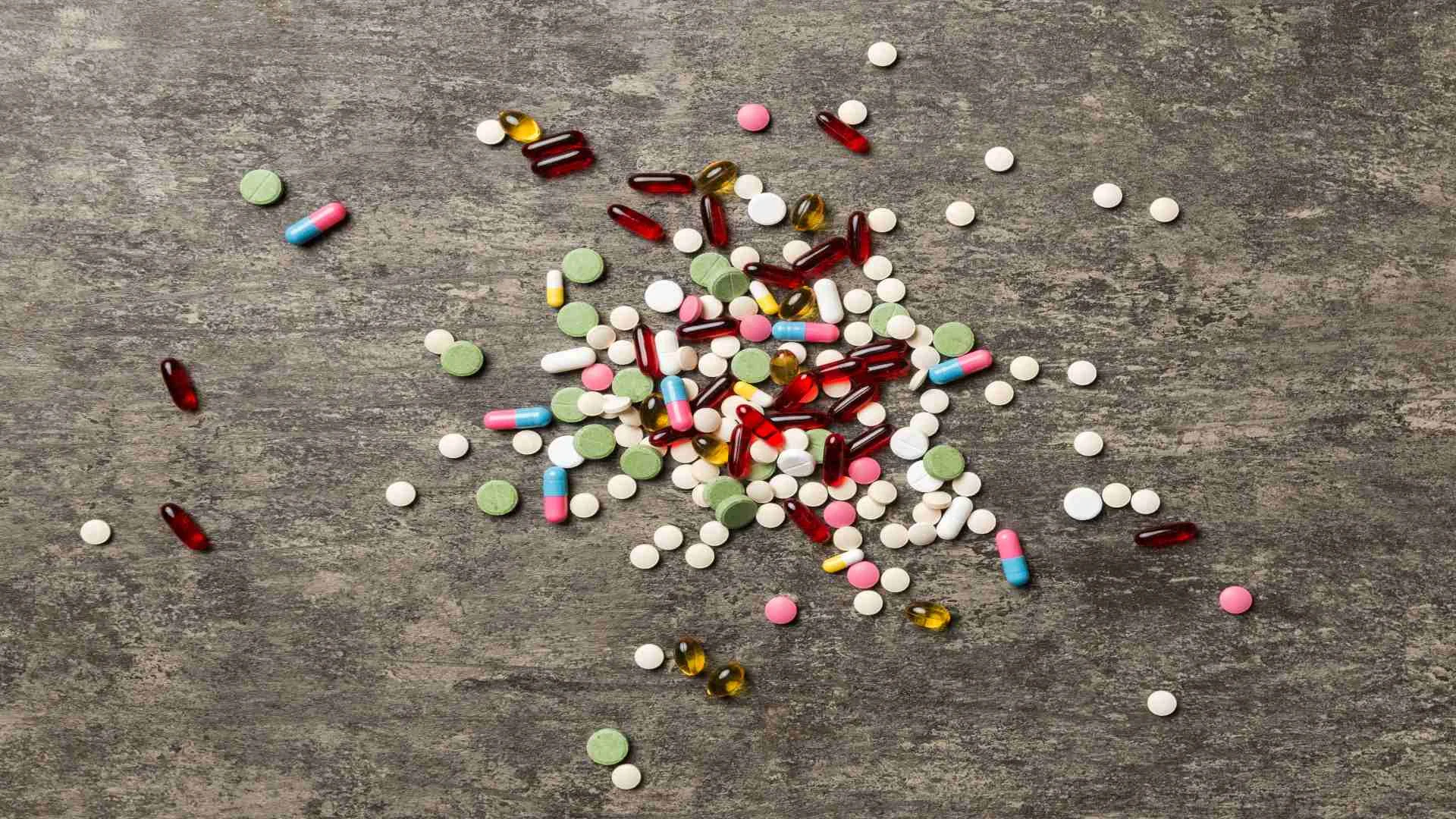 Benzodiazepines list visually represented by a colorful mix of pills and tablets on a concrete background, symbolizing the variety and availability of prescription sedatives.