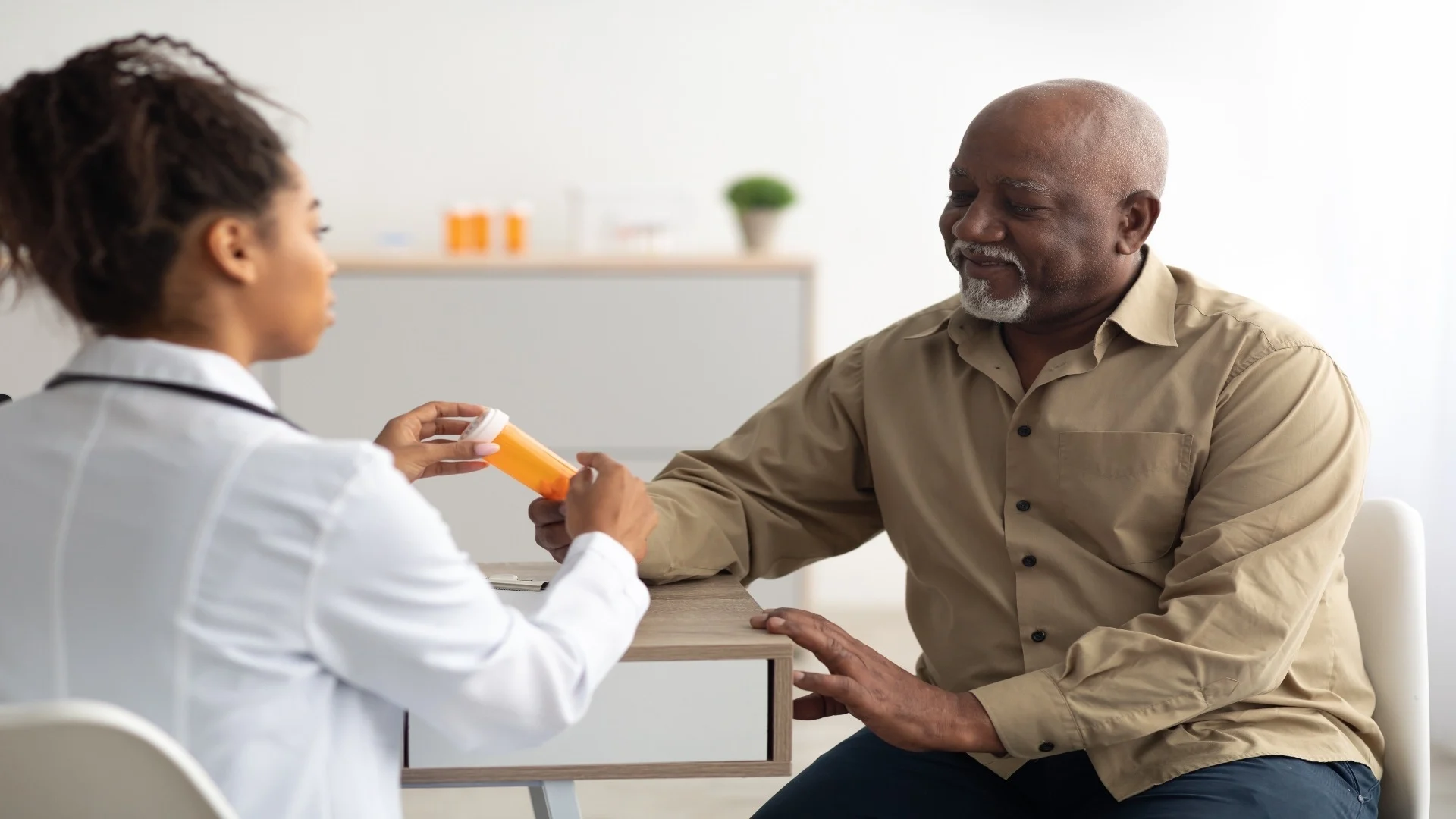 female-black-doctor-showing-pills-to-male-patient-2025-03-18-18-17-40-utc
