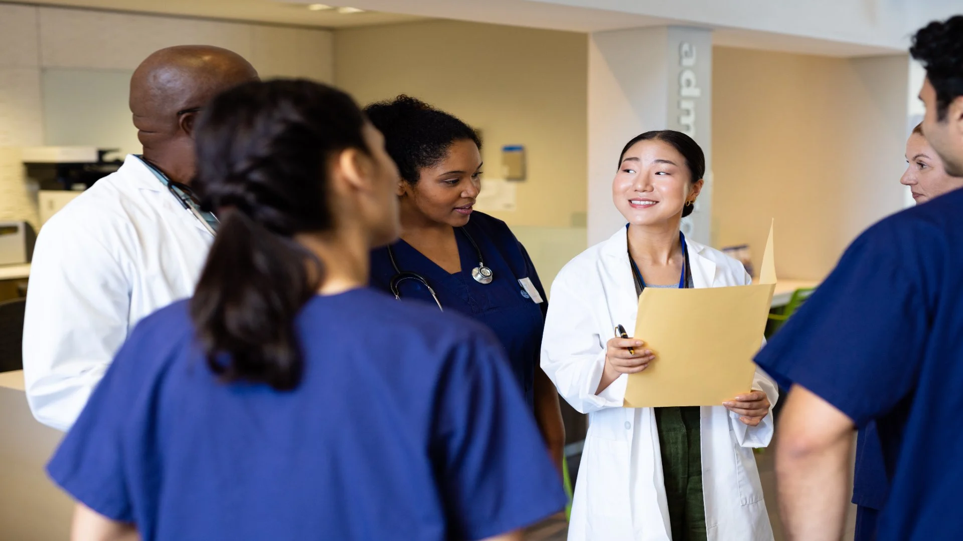 female asian doctor with a big bright smile making rounds with her residents