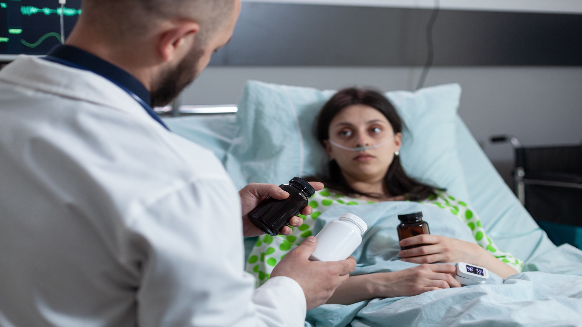 Doctor explaining hydrocodone medication options to a hospitalized woman receiving treatment.