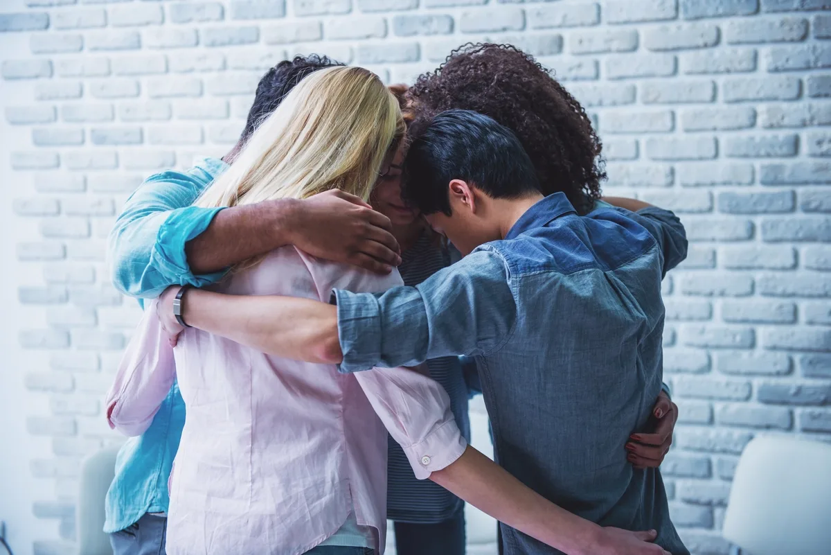 Outpatient Rehab: Group of friends hugging and supporting eachother Outpatient Rehab: Group of friends hugging and supporting eachother