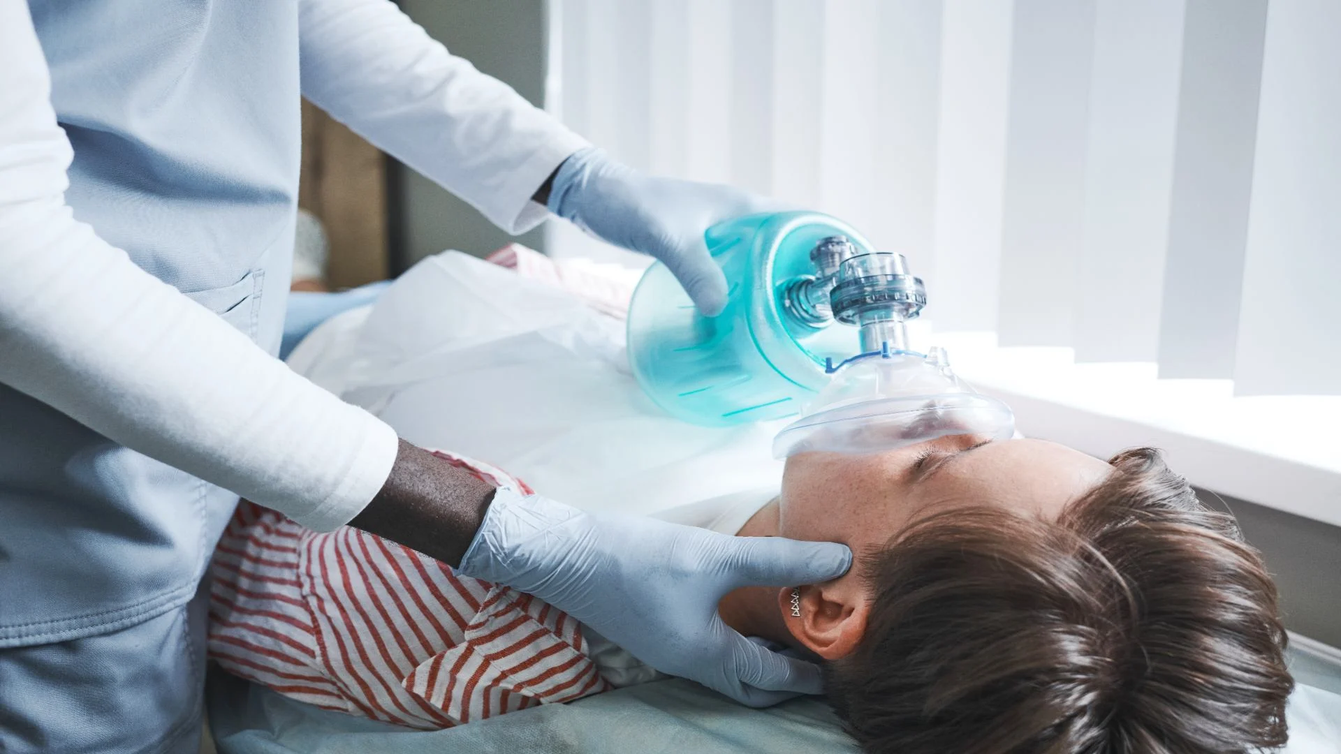 a doctor with a bag valve oxygen mask on patient's nose and mouth
