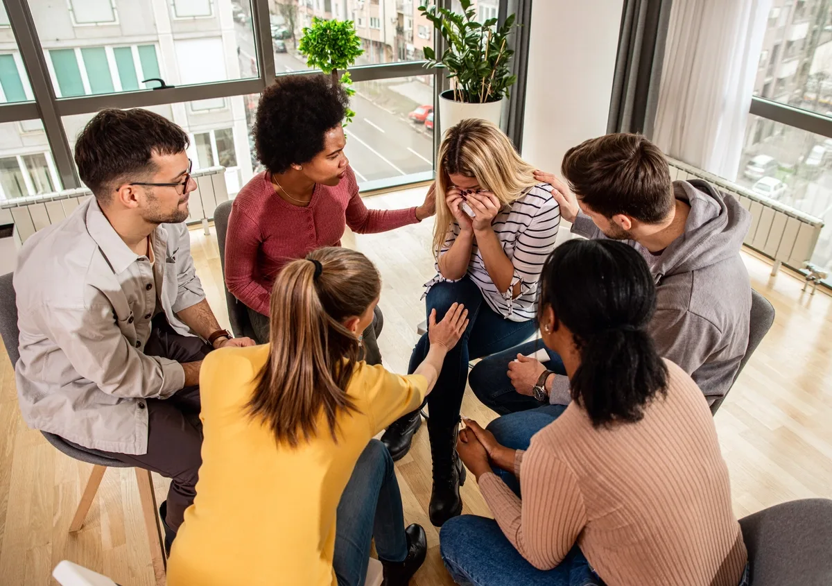 Alcohol Addiction: Group of friends supporting a woman crying