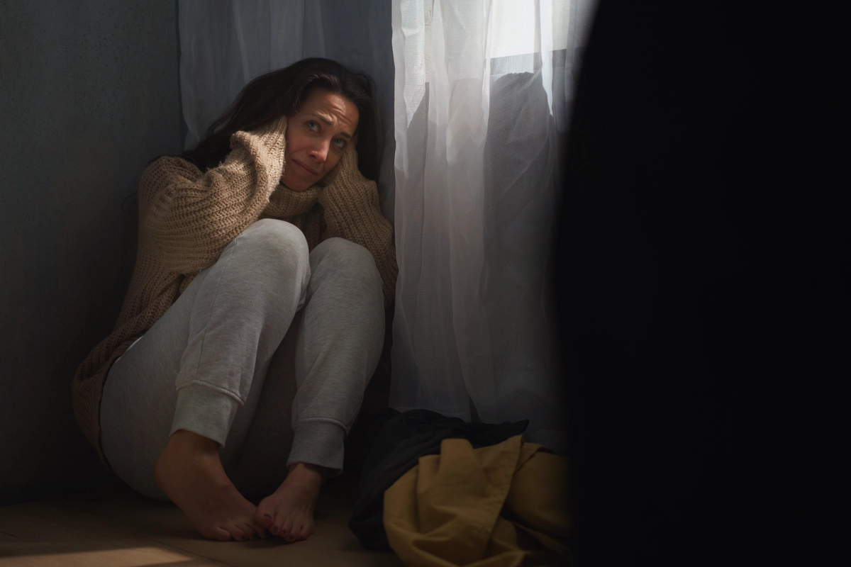 Residual Schizophrenia Patient Blocking Her Ears Sitting on Floor