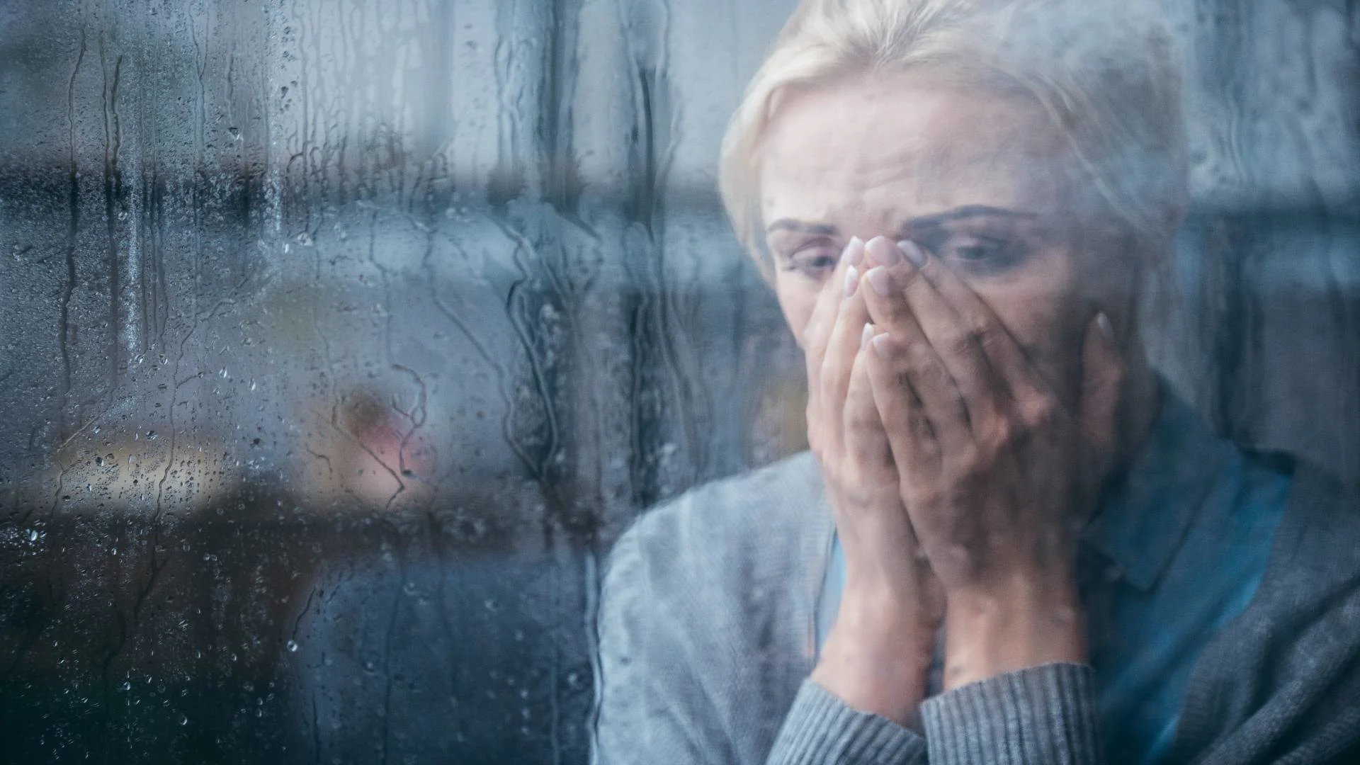 Sad woman crying behind a wet window, illustrating emotional struggles and the difficult question: how long does depression last?