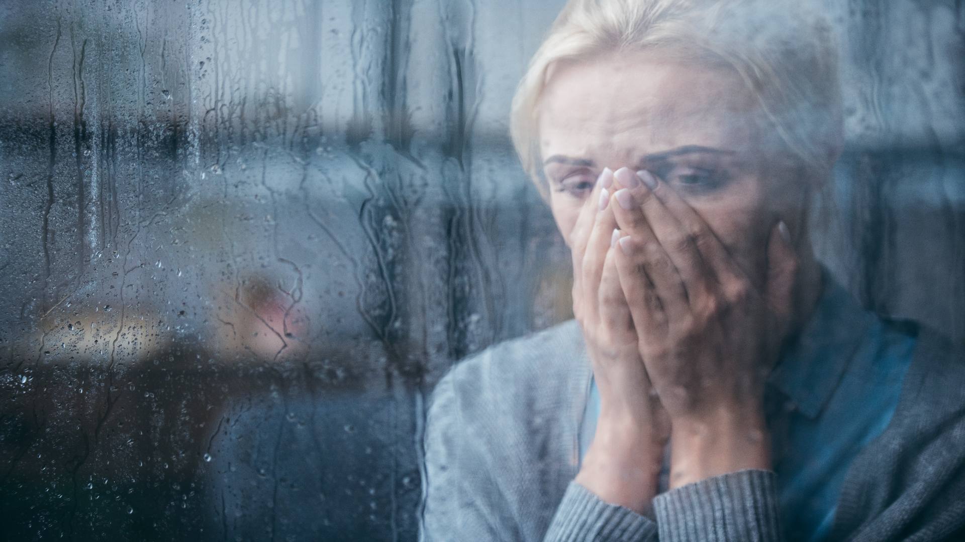 Sad woman crying behind a wet window, illustrating emotional struggles and the difficult question: how long does depression last? Sad woman crying behind a wet window, illustrating emotional struggles and the difficult question: how long does depression last?