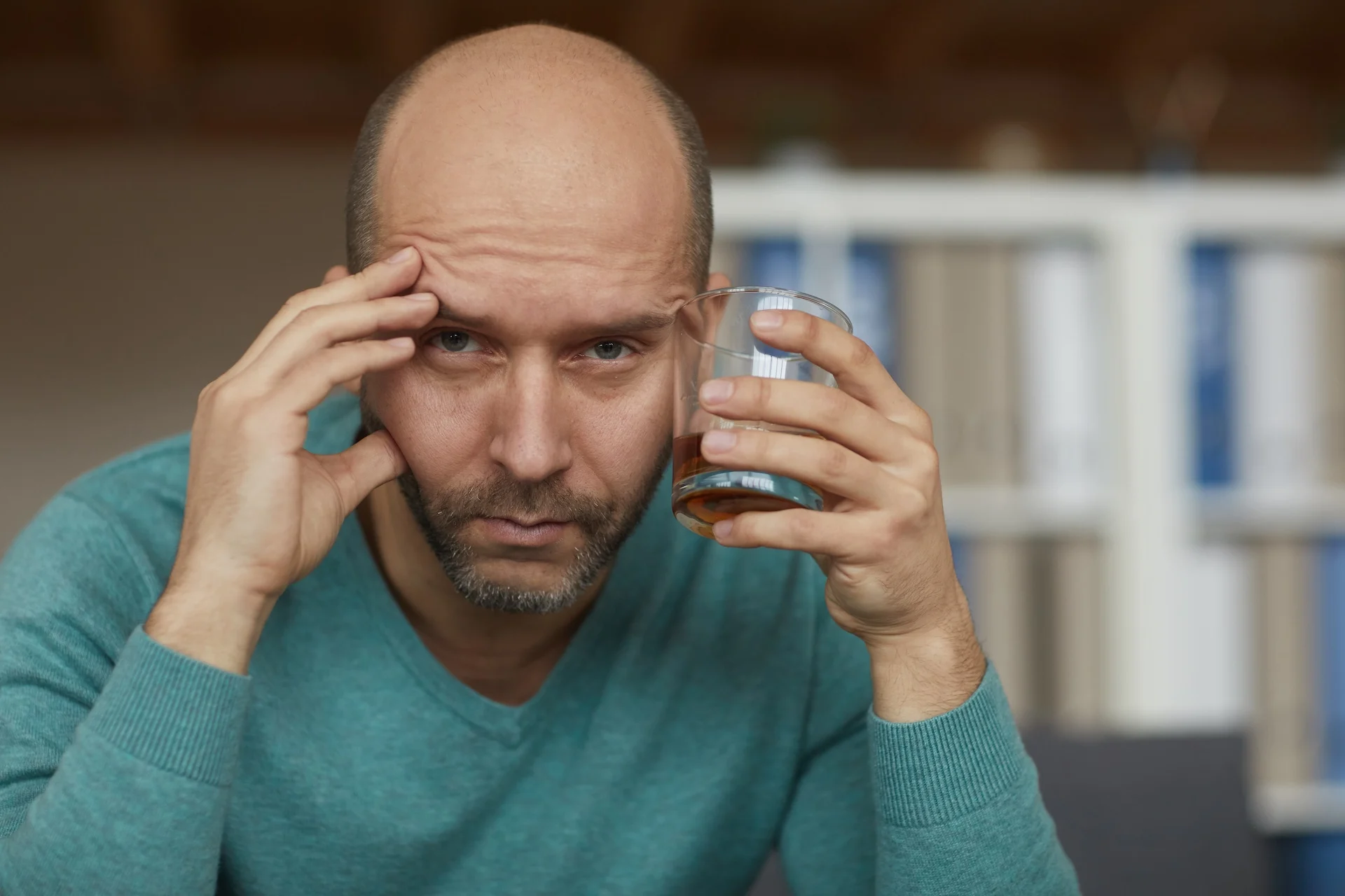 Gabapentin and alcohol interaction causes severe symptoms in man experiencing dizziness, confusion, and headache while holding glass of whiskey at home