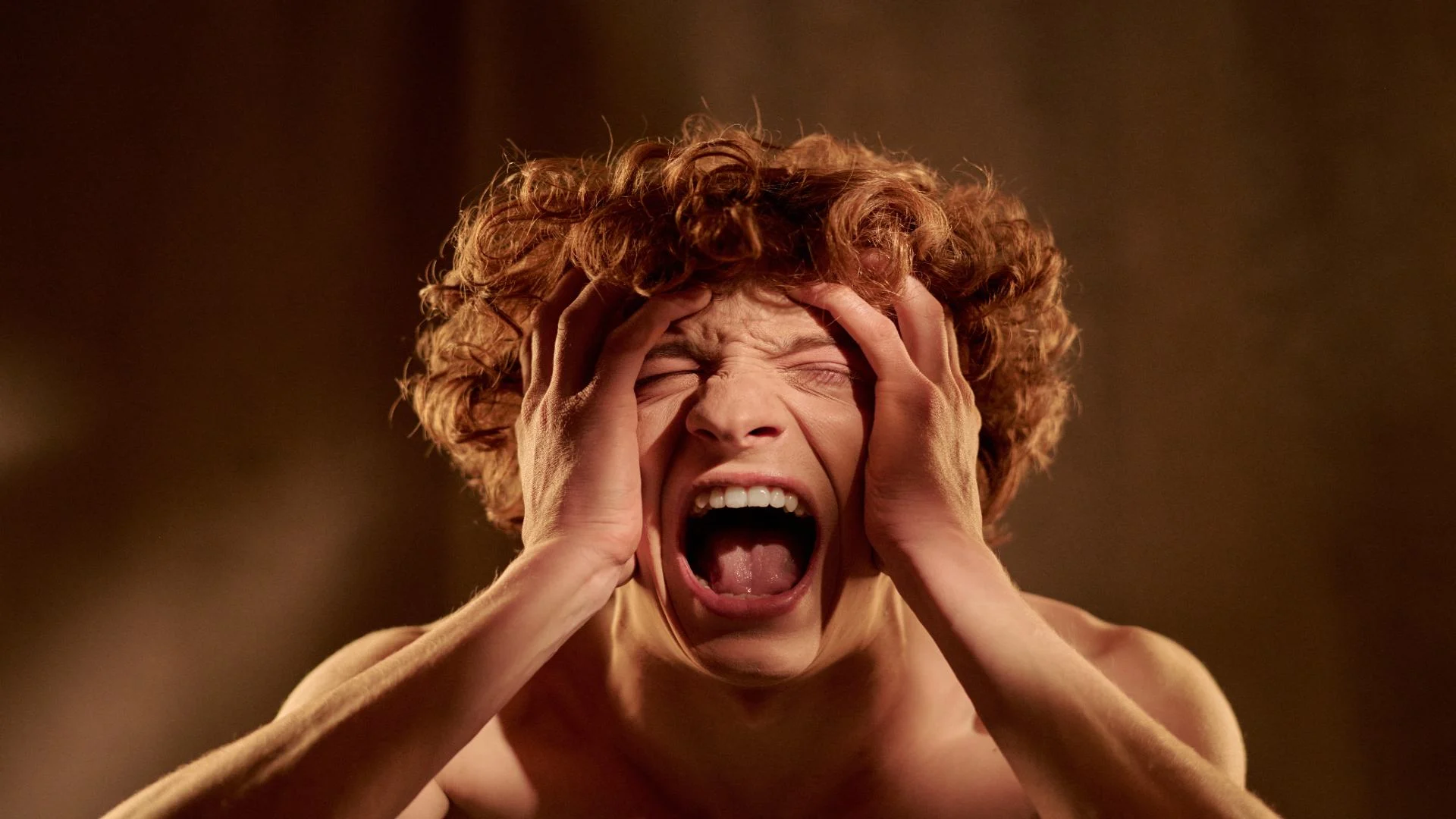 Young man screaming in distress with hands on his head, illustrating the intense and sudden fear of a panic attack.